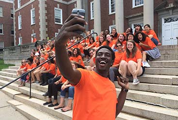 male student taking selfie with group of students on outdoor steps