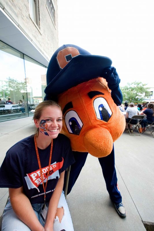 A student poses with otto the orange at a school picnic