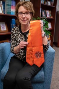 Amie Redmond holding a graduation stole given to her my a student