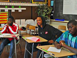Young men listen to a student share his lyrics during a self-expression session.