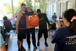 two male students pose with otto at a community event in huntington hall