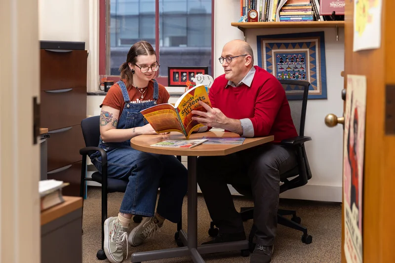 A professor and undergraduate sit at a desk