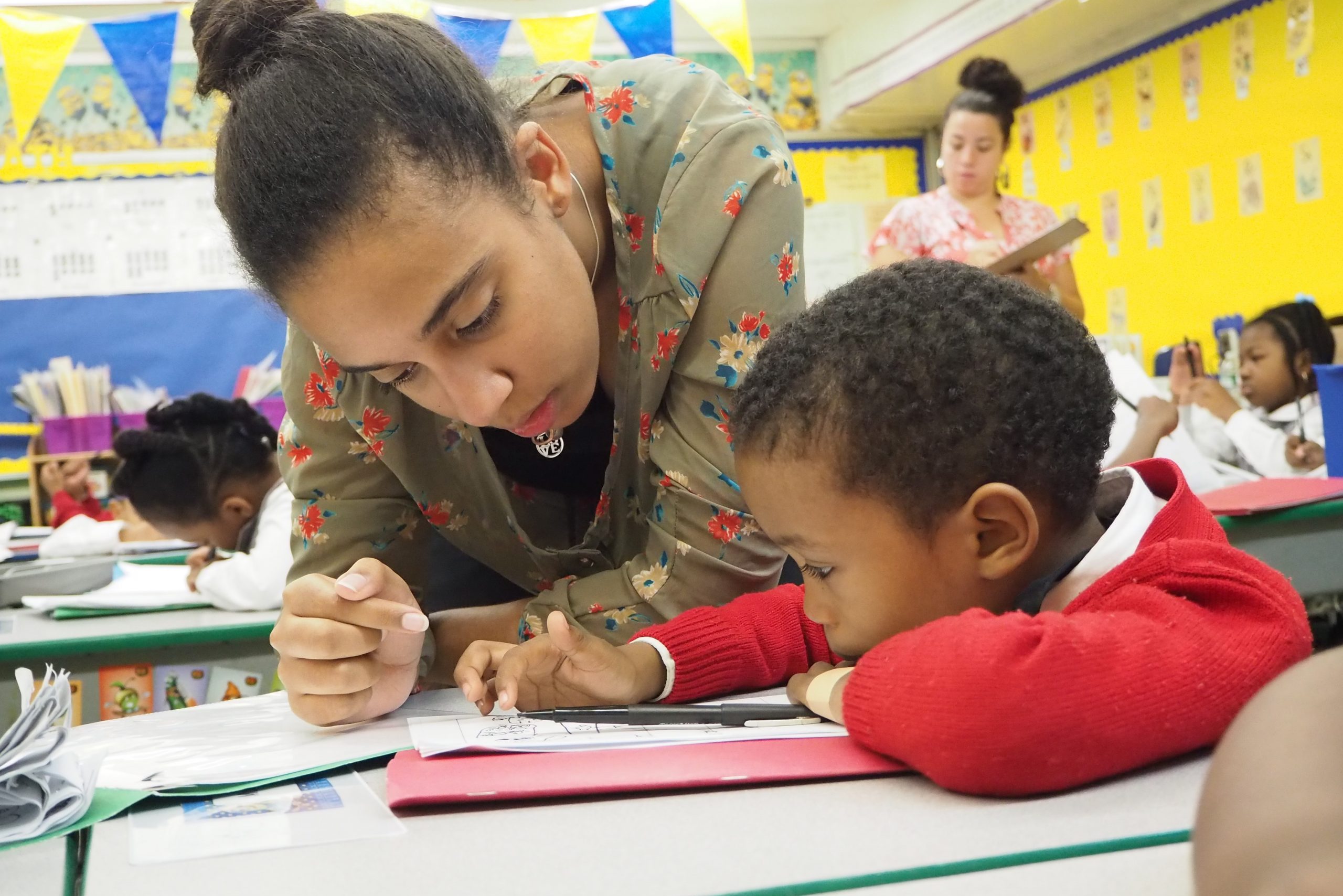 a black undergraduate student works with a preschool student