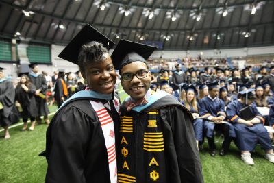 two master's degree graduates smile at the camera at convocation