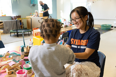 Emily Liu helps a student at a desk