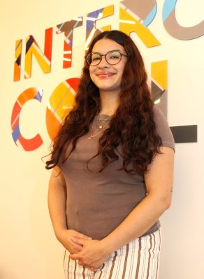 Aaliyah Muolo Vergara stands next to an Intercultural Collective sign
