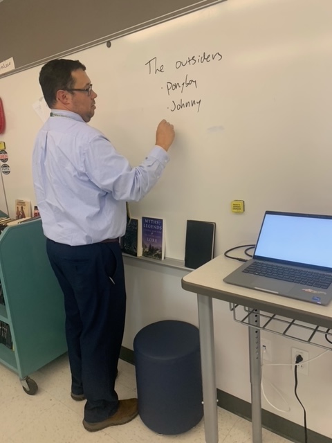 A Native American teacher stands at a whiteboard