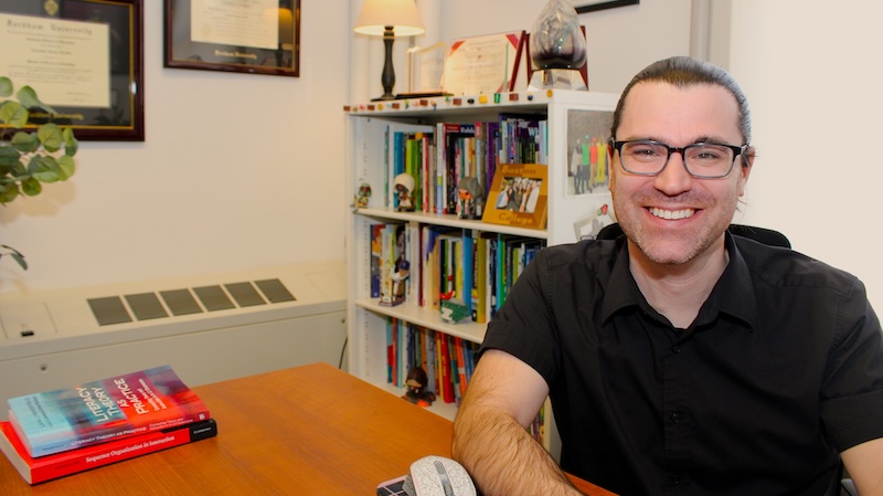 Professor Alex Corbitt sits at his desk