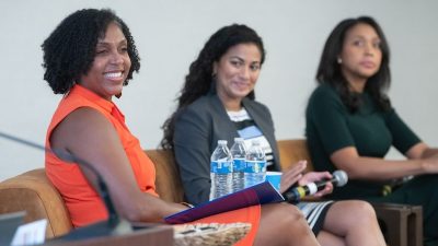 Three women sit on a panel