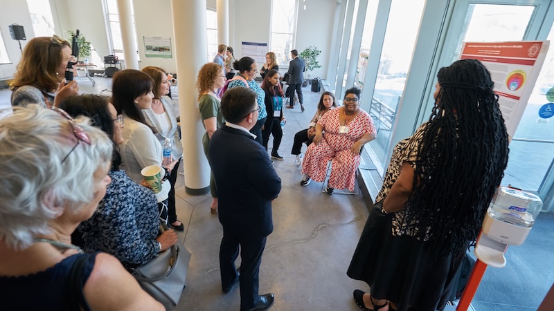 A black woman researcher takes questions about a research poster