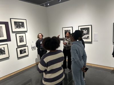 Students and a teacher look at art works in a museum