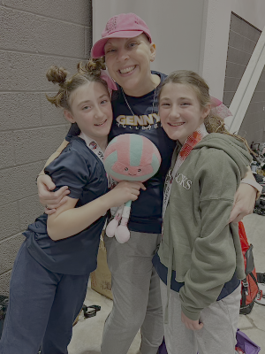 A mother poses with two twin daughters holding a volleyball