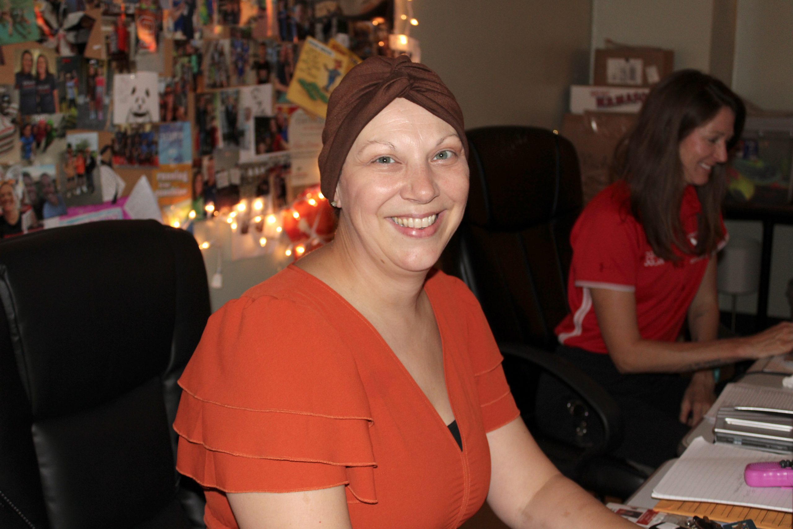 A teacher in a headwrap sits at her desk