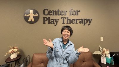 Coco Wing Yun Wong next to a sign that reads Center for Play Therapy