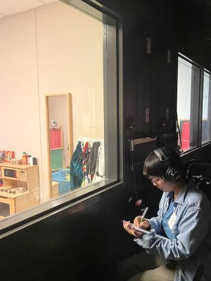 Coco Wing Yun Wong takes notes outside a play therapy room