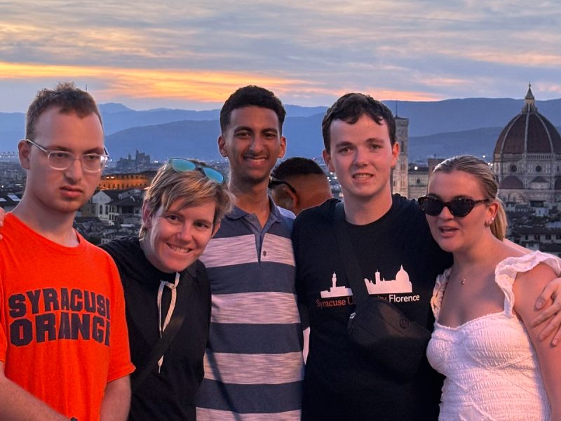 A group of students pose with countryside in the background