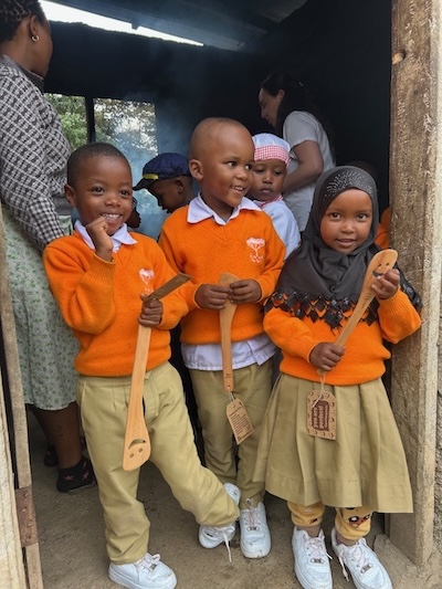 Three students stand in a doorway with spatulas