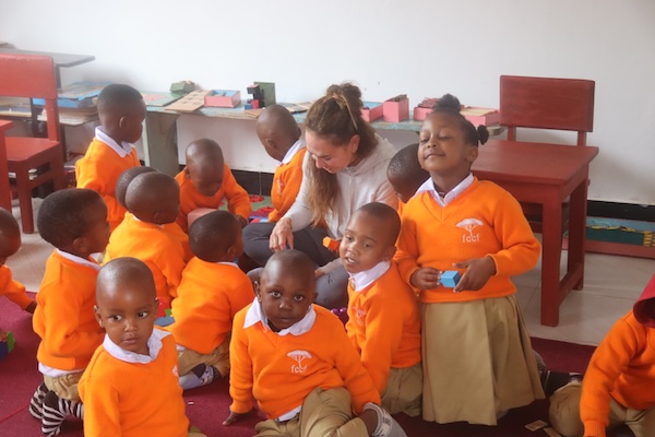 A woman surrounded by happy kindergartners