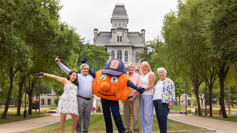 Generations of a family pose with Otto the Orange
