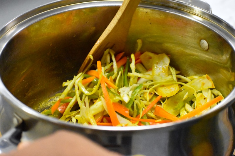 Chopped vegetables being stirred in a pot