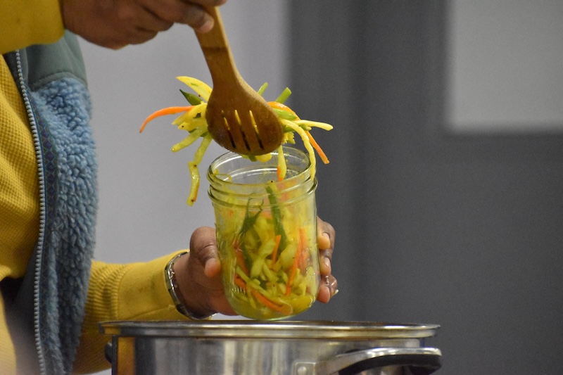 Vegetable mix being spooned into a jar