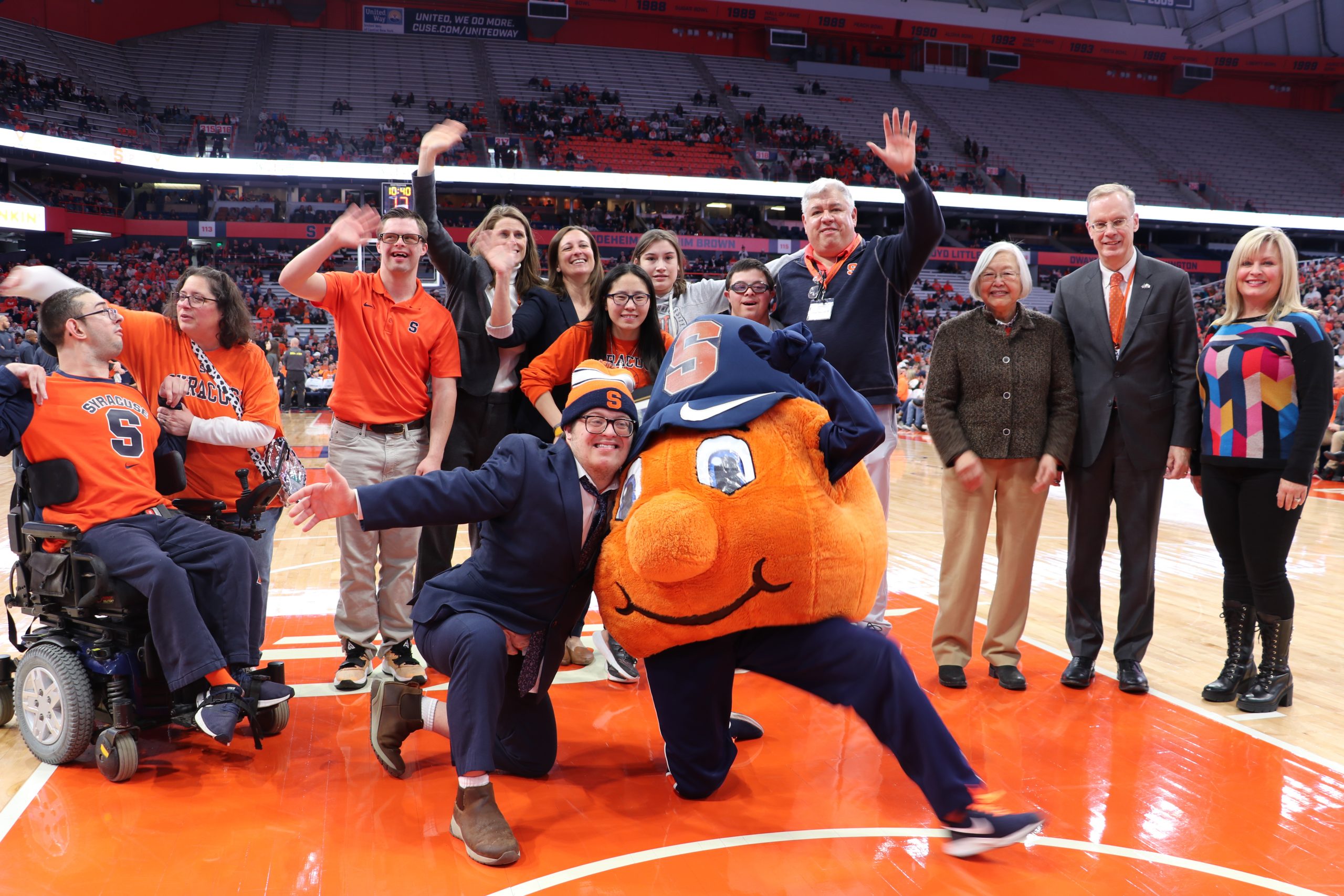inclusive u students, staff, and board members pose with otto the orange on the dome basketball court