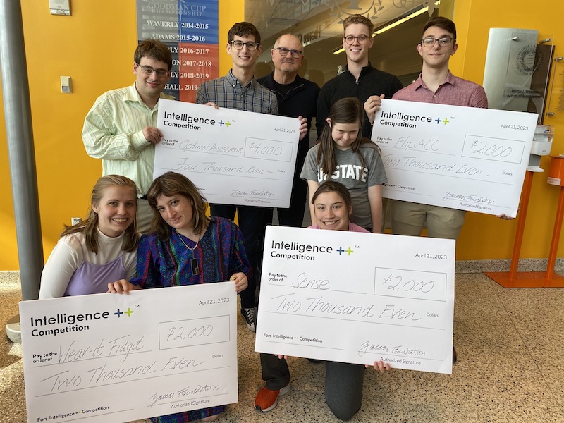 A group of Intelligence++ students with their giant checks