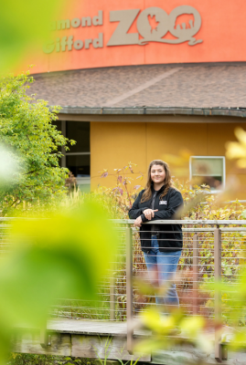 Mary Hillebrand stands beneath sign for Gifford Zoo