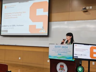 Jing Lei standing with a microphone at a podium