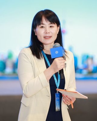 Jing Lei stands with a microphone at an AI conference