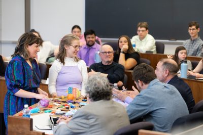 Two students show an exhibit to a panel of judges