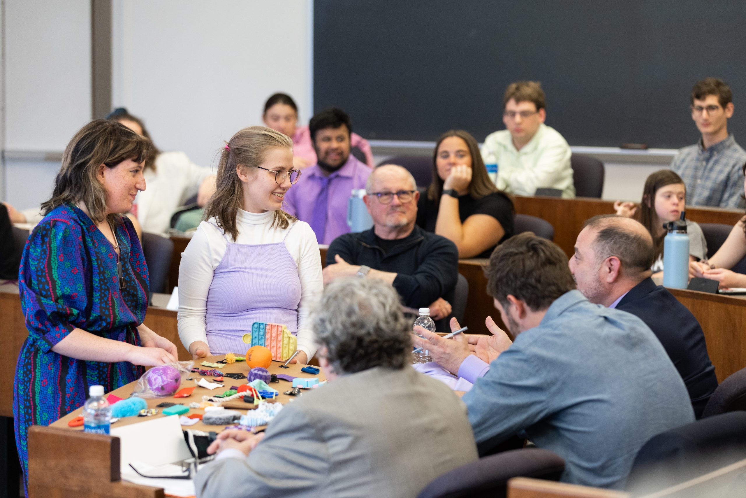 Two students show an exhibit to a panel of judges