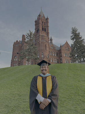 A college graduate poses in front of an old academic building