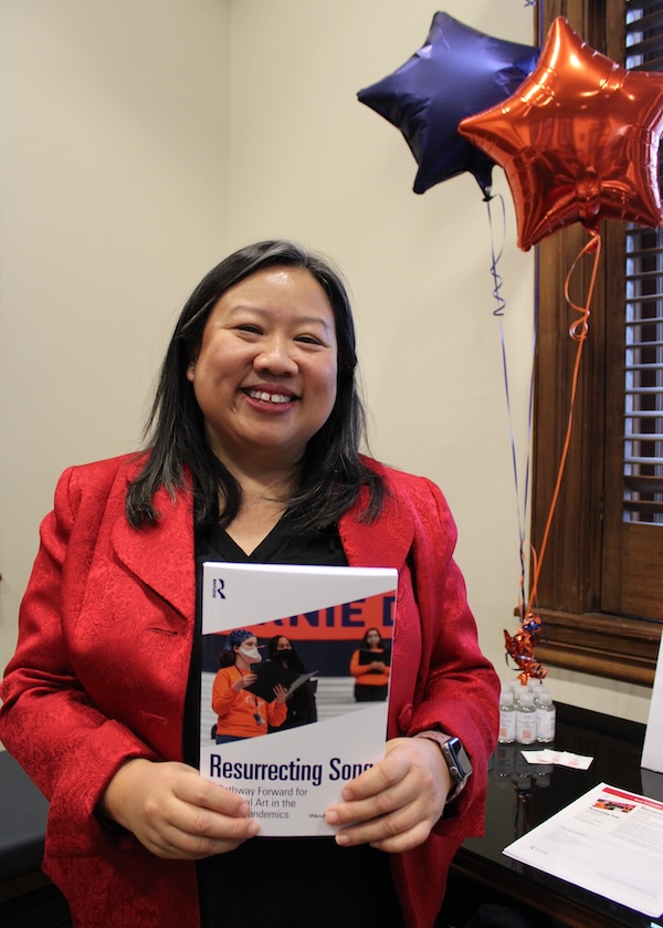 Professor Wendy Moy holding a copy of Resurrecting Song