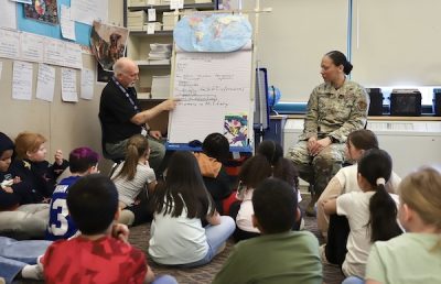A National Guardswoman talks with a teacher and his class of middle-graders