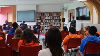 Three members of the Syracuse 8 speak to a room full of middle school students