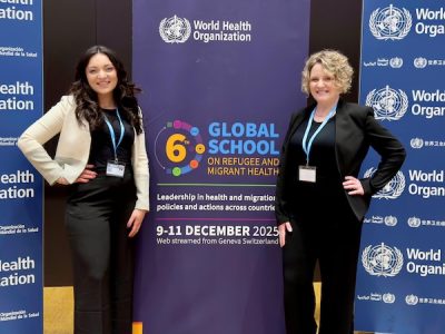 Two social workers stand in front of a conference banner
