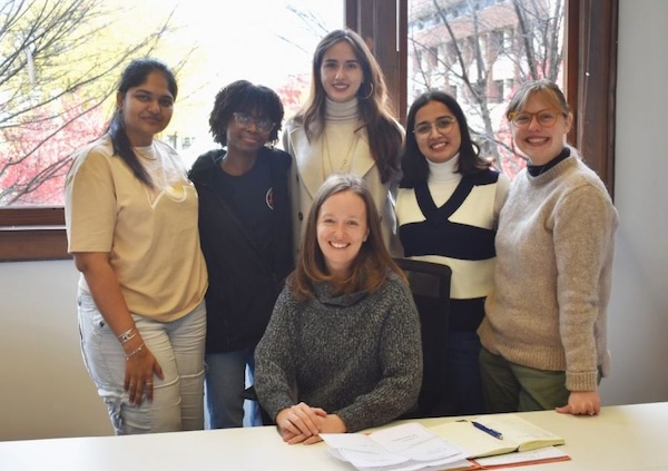 A professor sits in front of five graduate students