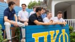 A group of Greek brothers next to their fraternity sign