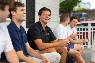 A group of Greek brothers seated outside their fraternity house