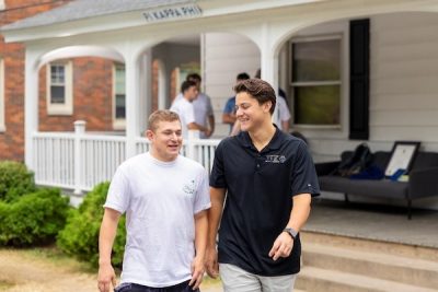 Two Greek brothers walking outside their fraternity house