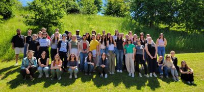 A large group of students stand in a field