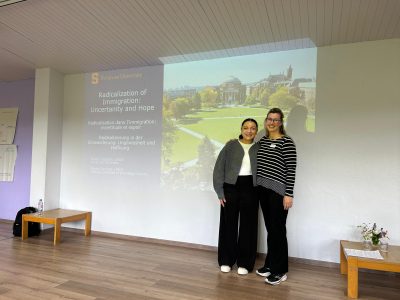 A tusdent and professor stand next to a screen