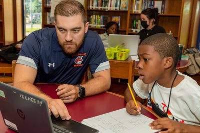 Teacher showing student something on a laptop.