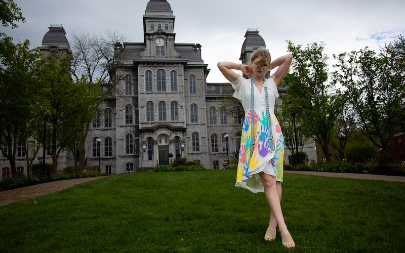 Young woman stands in front of Syracuse University Hall of Languages