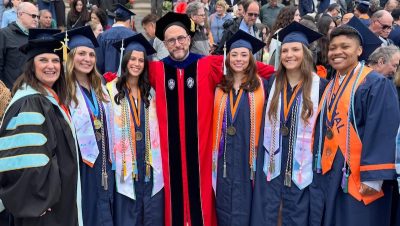 Students and faculty in a group shot wearing commencement regalia