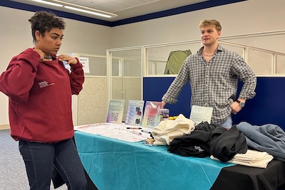Two students discuss clothing at a table