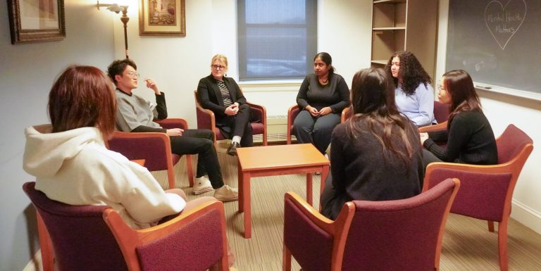 group of counseling students in a counseling center talking in a circle of chairs