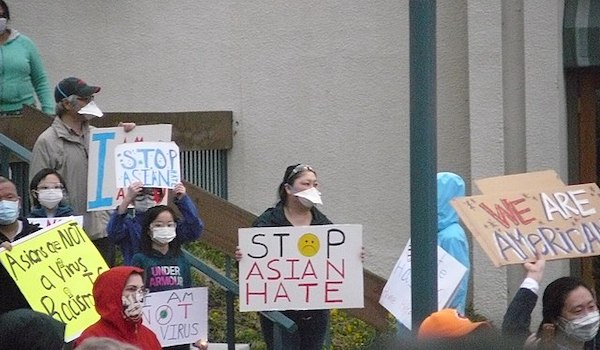 Anti-Asian hate protestors hold signs.