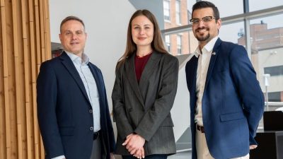 One female and two male professors pose for a photo